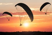 Silhouette Of Paragliders At Sunset